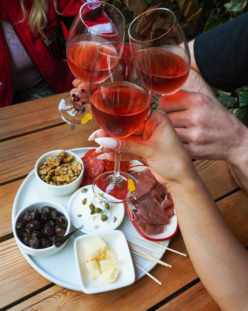Four glasses of rosé clinked together over an antipasti platter