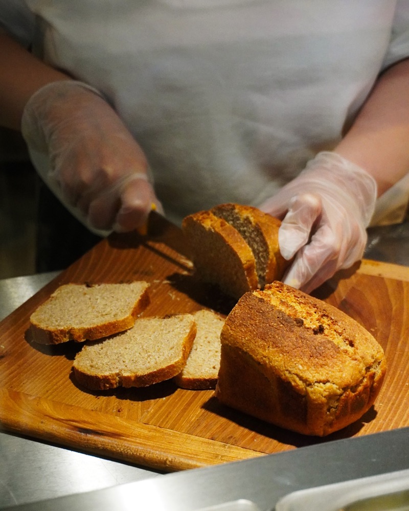 Fresh bread being sliced on a wooden board