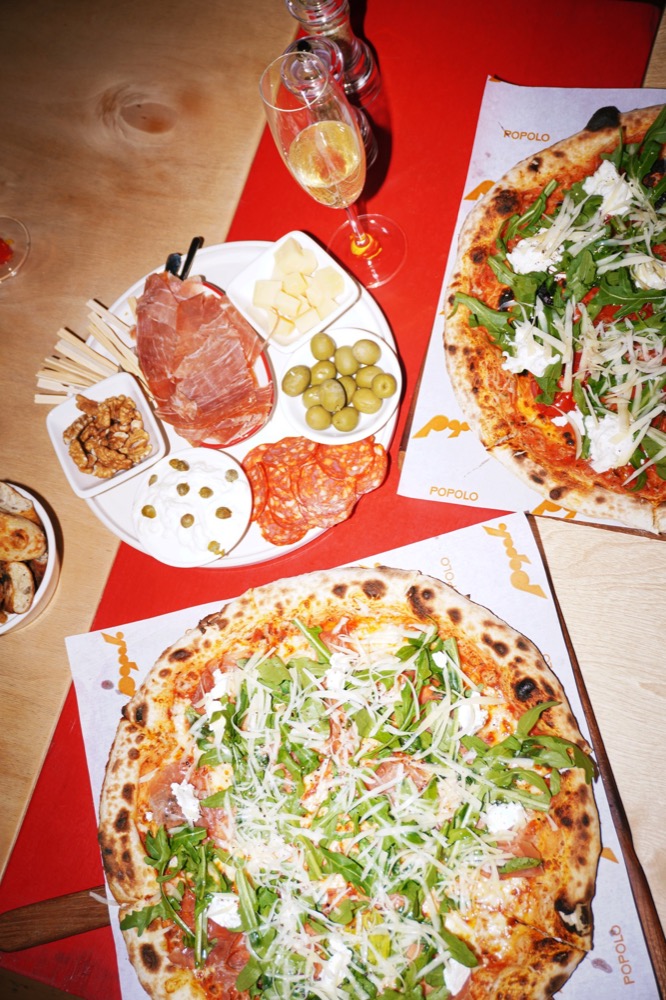 Two pizzas and an antipasti board on the table