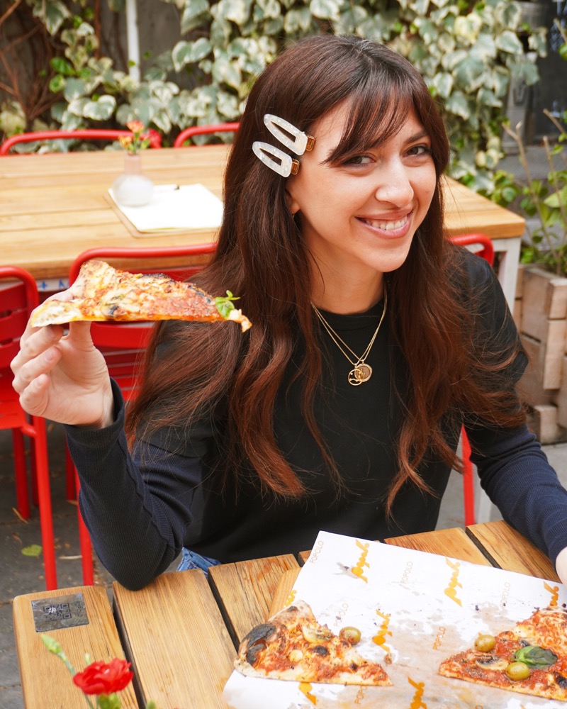 Guest holding a slice of pizza outdoors