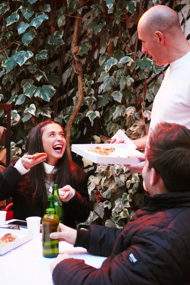 Guests sharing pizza in the ivy-covered courtyard