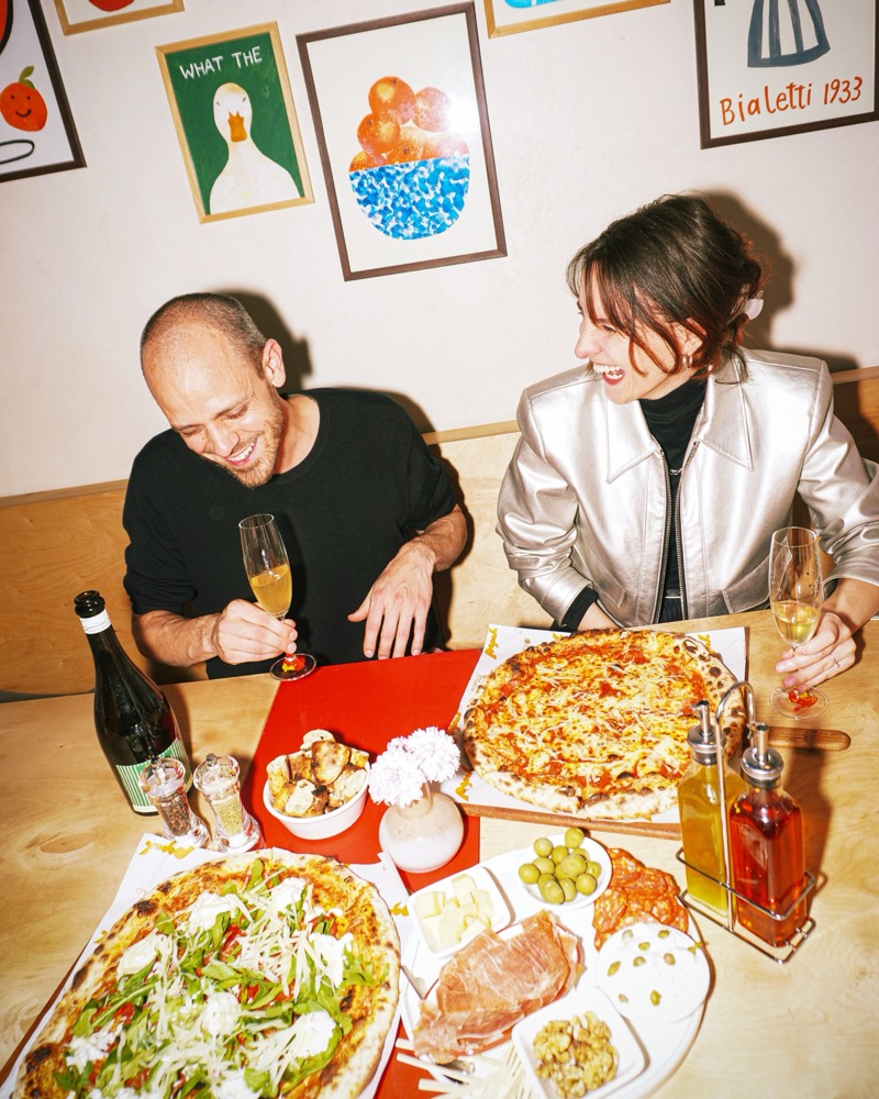 Friends laughing over pizza and wine inside Popolo